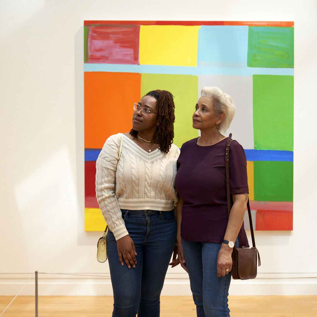 Two Black women, one older one younger, dressed in casual clothing, stop to look at abstract, colorful, work on view in The Met's Modern and Contemporary Galleries.