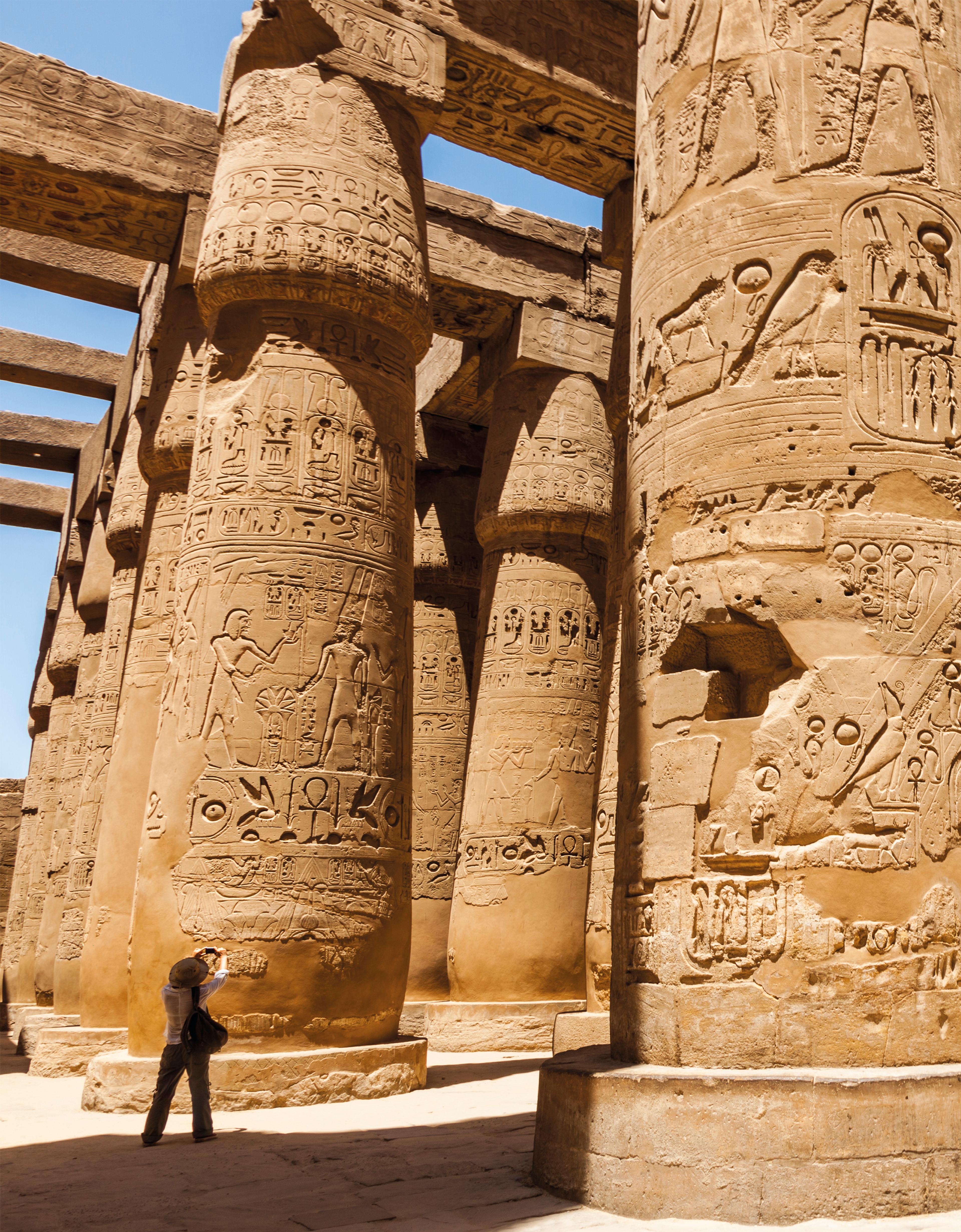 A person looks up to photograph the Karnak columns in Egypt.