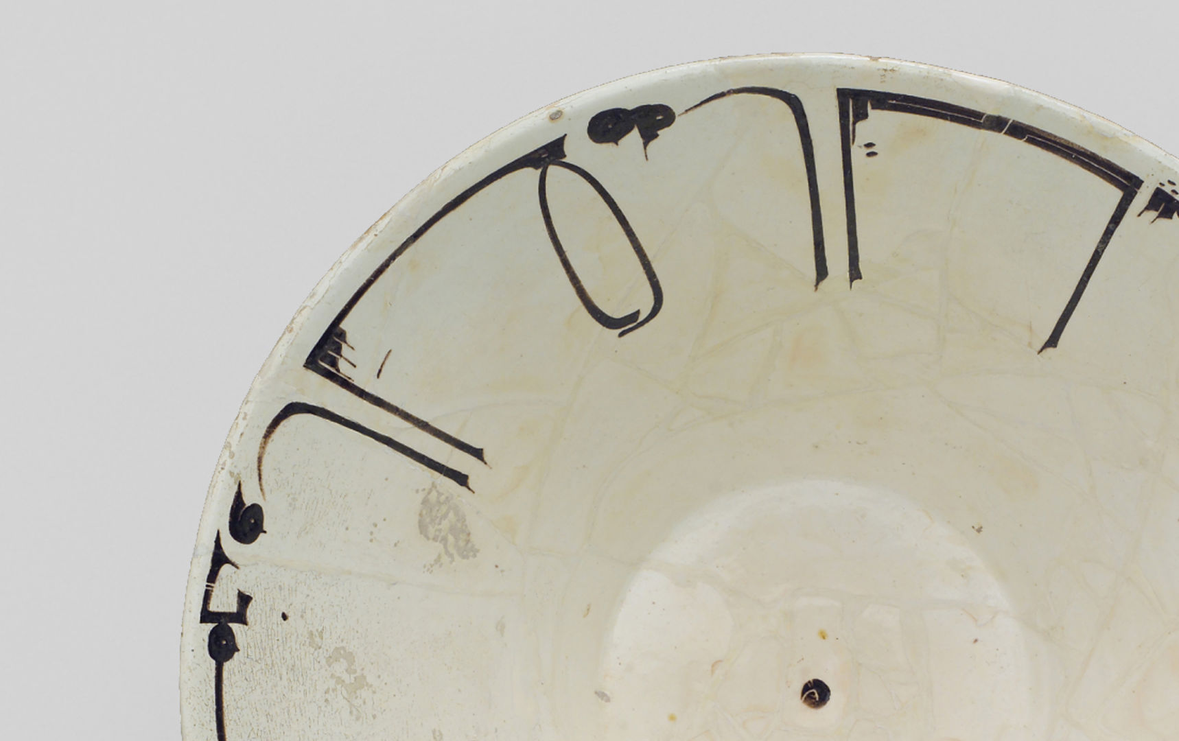 Off-white ceramic bowl with Arabic inscription photographed on a beige background