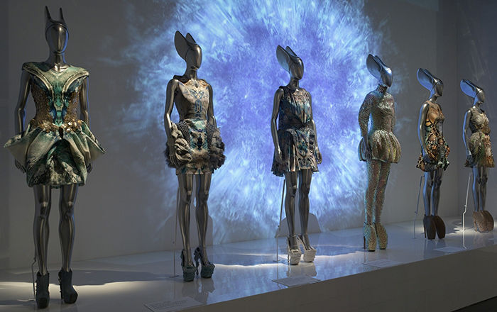 Mannequins lined up on a display wearing futuristic, metallic outfits.