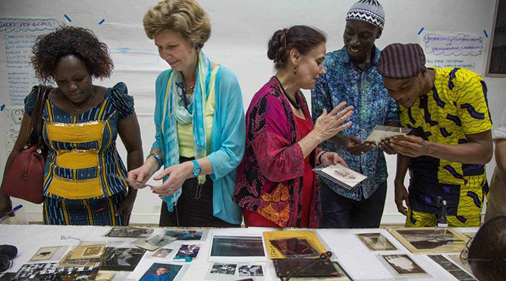 A group discusses and looks at an array of photographic material spread out across a large table.