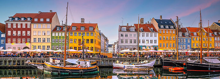 View of a row of brightly colored houses behind a river in Copenhagen