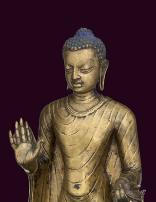 A golden statue of buddha in front of a dark purple background.
