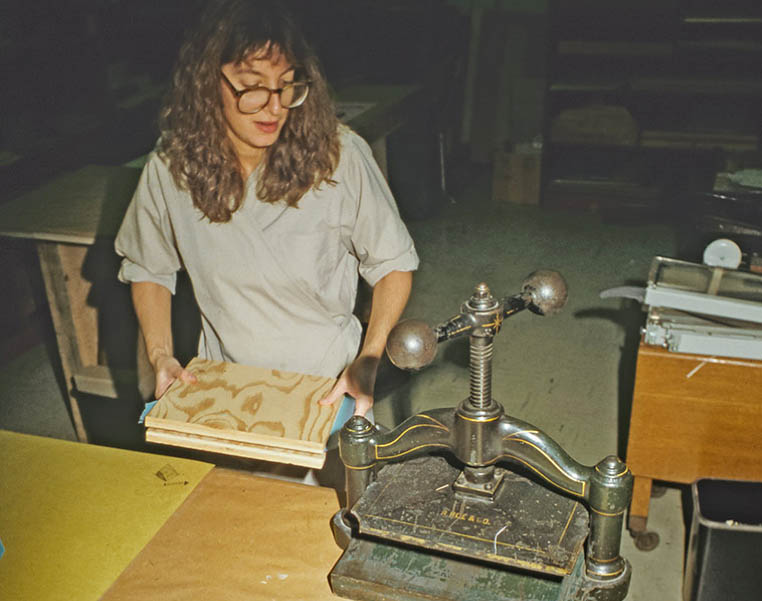 A conservator placing a book into a bookbinding press.