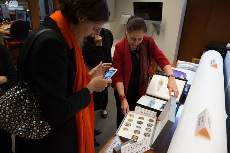 A group of women carefully examines a case of circular photographic objects, taking pictures of them