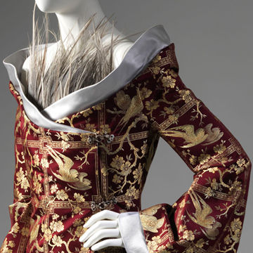 Detail view of an elegant red-and-gold ensemble by Alexander McQueen
