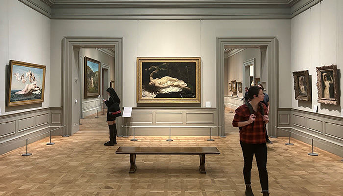 A view of guests looking at artworks in Gallery 811, including Cabanel's "The Birth of Venus", Courbet's "Woman with a Parrot", "The Woman in the Waves", and "Woman with a Flowering Branch".