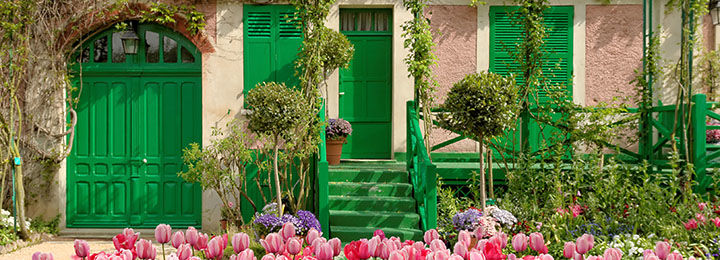 View of house with green doors and pink tulips in Monet's Giverny garden