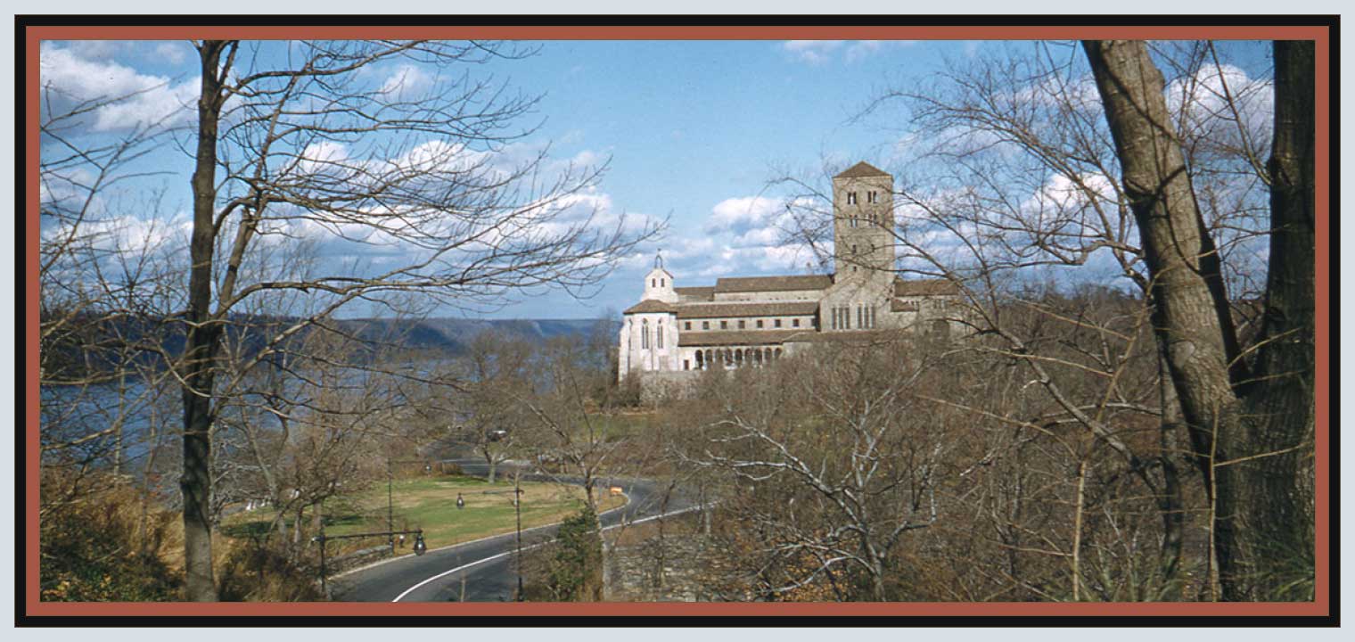 A windy road leads up a hill to towards a castle-like building set against a river backdrop and distant cliffs on the river coast on a partly cloudy day. Bare winter trees flank to view on either side. The image is framed by a light blue, black, and reddish-brown tri-color border.