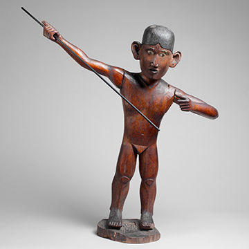 Wooden male figure holding a pole or spear as if he's about to spear a fish