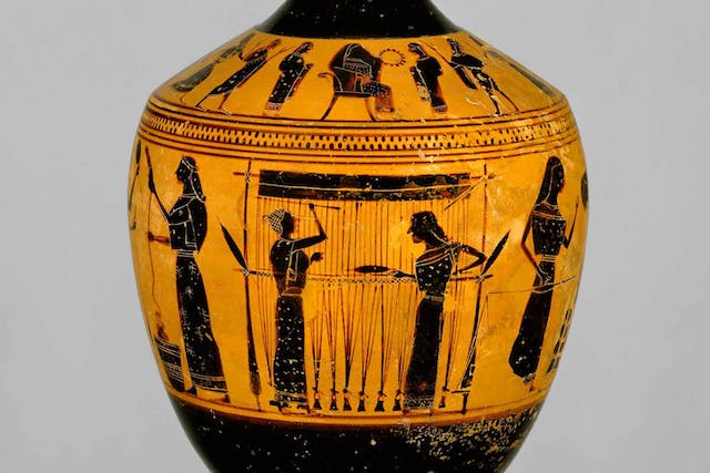 Terracotta lekythos, or oil flask, with black figures of women weaving on a loom on orange ground.