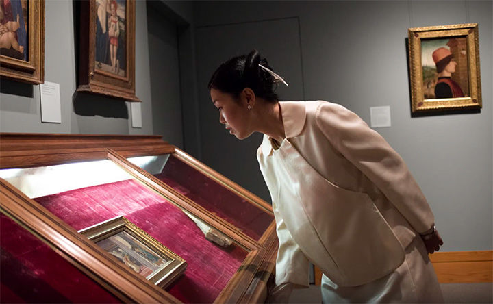 Mariko Mori looking down at a painting in a display case.