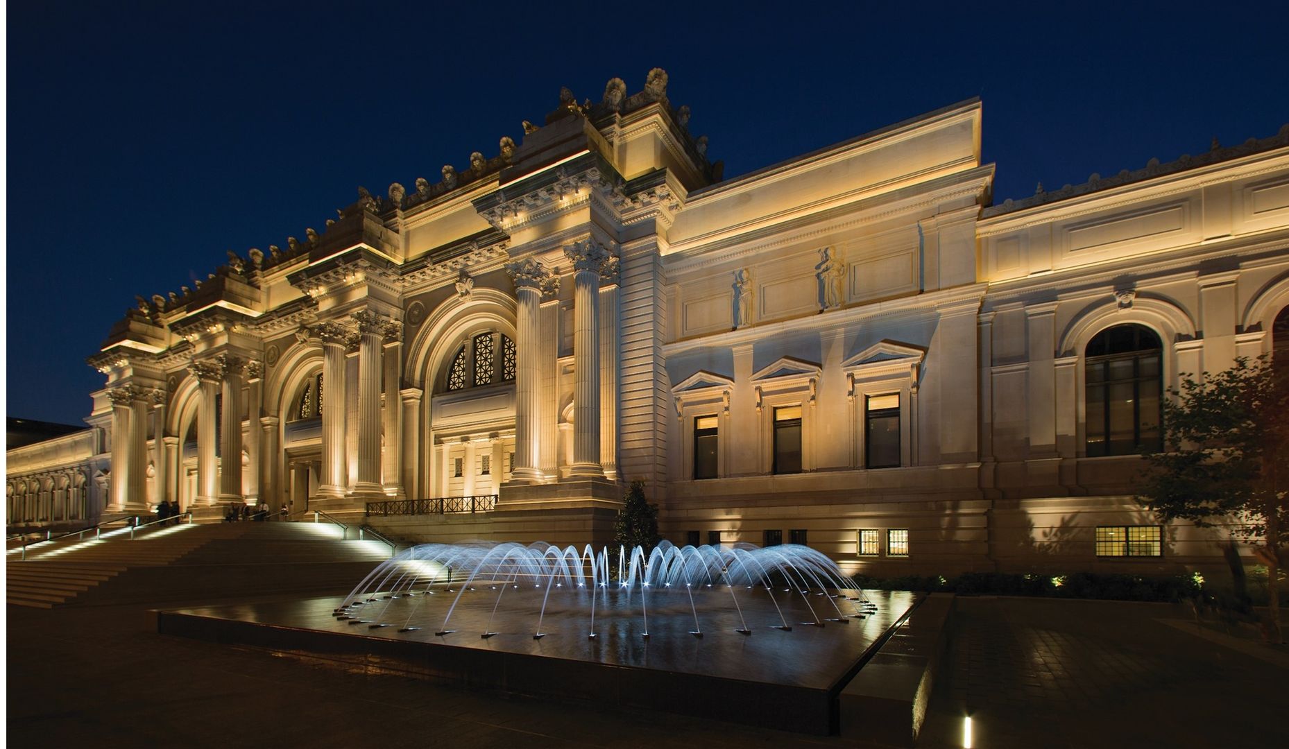 The illuminated façade of The Met Fifth Avenue at night.