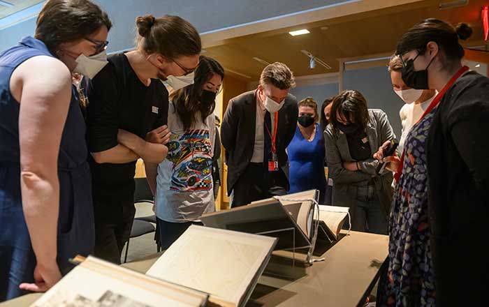 Met staff members and fellows looking down at a large manuscript on display