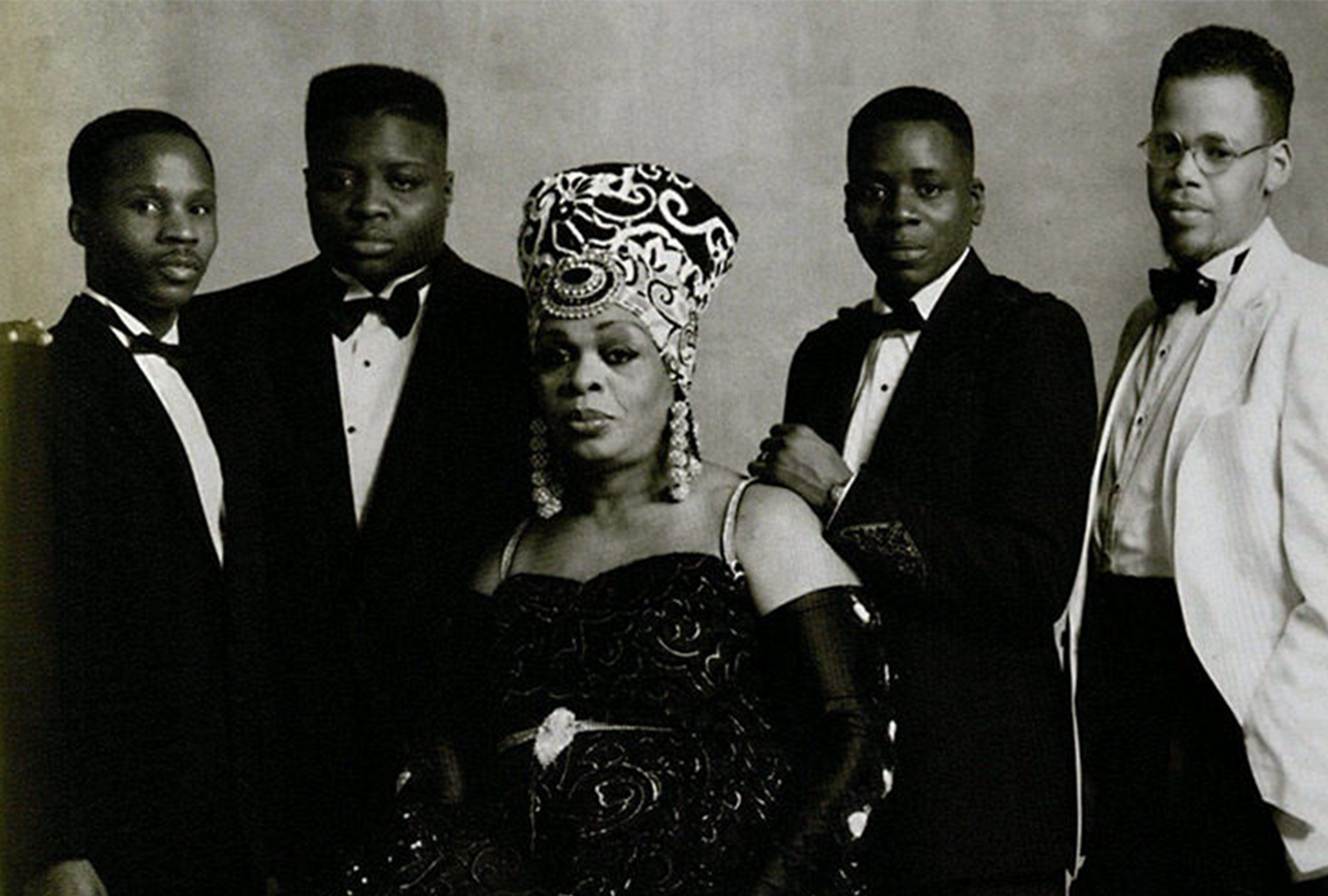 Black and white image of 5 Black queer folks posing from "Voguing and the ballroom scene of New York City" 1989-92 (London: Soul Jazz Records, 2011)